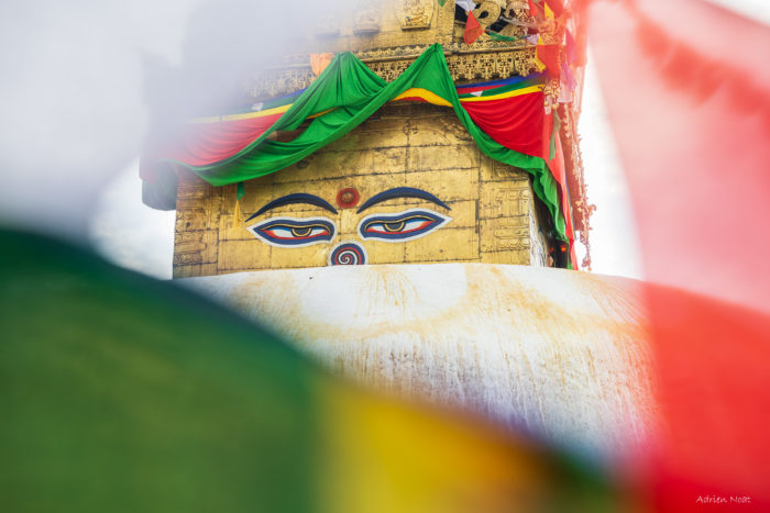 Yeux du stupa de Boudhanath cadrés entre des drapeaux de prières à Katmandou au Népal