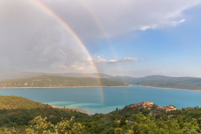 Arc-en-ciel au-dessus du lac de Sainte-Croix dans les gorges du Verdon, avec ciel d’orage, eau turquoise et paysage de Haute-Provence.