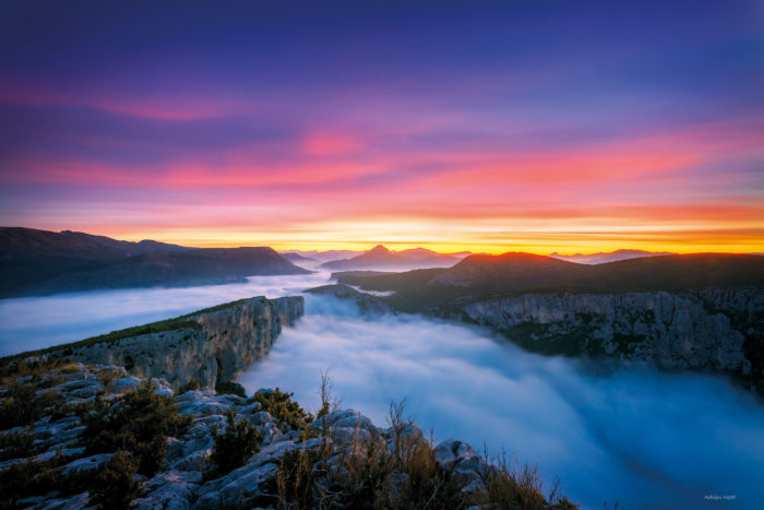 Mer de nuages dans les gorges du Verdon à l’aurore sous un ciel violet, rose et doré